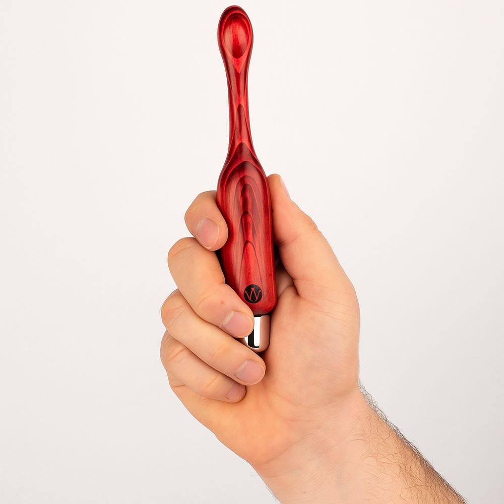 Eine Männerhand hält einen Beckenbodentrainer der Firma Waldmichlsholdi  Modell Frettchen aus Holz in der Farbe rot in der Hand.