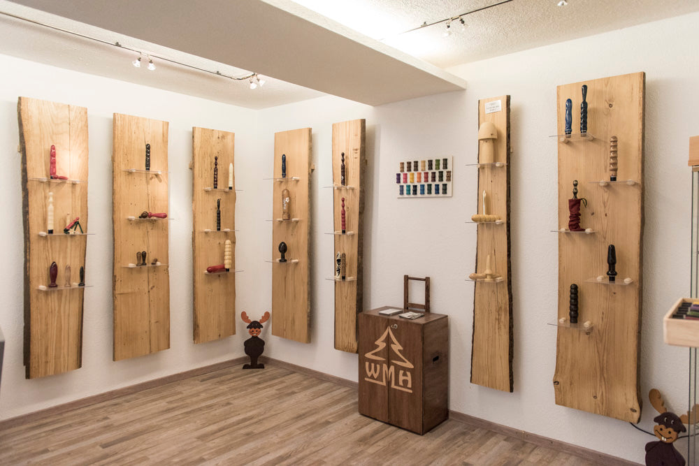 Ein Verkaufsraum mit einzelnen Holzbrettern an der Wand auf denen Holzdildos und Holzvibratoren von WaldMichlsHoldi ausgestellt sind.