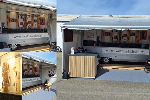 Ein Mobiler Verkaufsstand mit einer modernen Auslage. In der Auslage sind Holzdildos und Holzvibratoren ausgestellt von der Firma WaldMichlsHoldi.